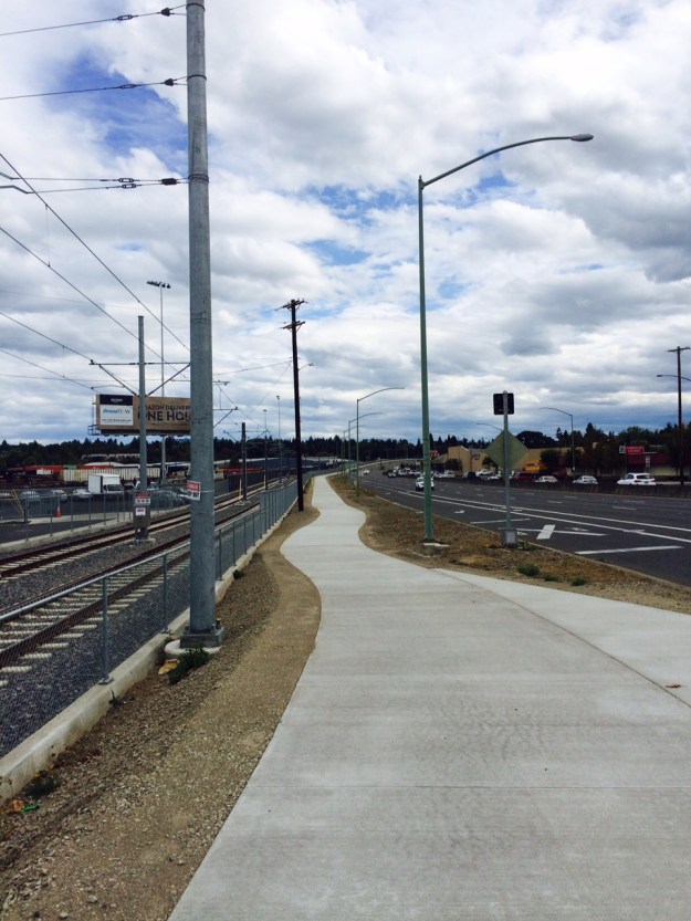 This new path separates the new rail lines from Mcloughlin Blvd. between SE 17th and Harold St. Here the concrete walk sits above the previous grade. The left edge show how high and is accomplished by 'layering' gravel base material in 'lifts' each of which are compacted for stability.